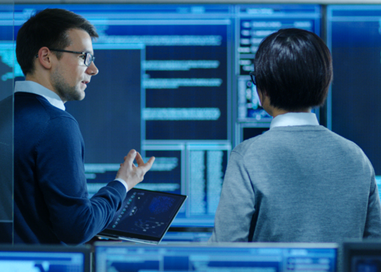 Two IT professionals collaborating on data analysis, discussing efficiency.