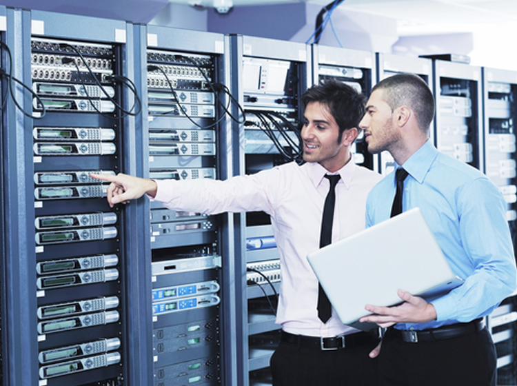 CFO and CIO collaborate in a server room, discussing IT infrastructure.