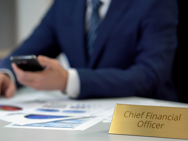 Businessman in suit reviewing data on phone with Chief Financial Officer name plate