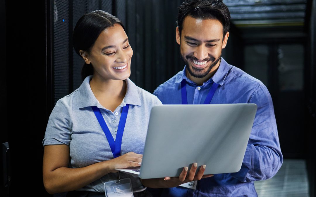 IT professionals reviewing data on a laptop in a server room