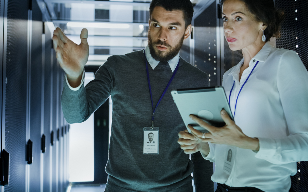 IT consultant explaining data to businesswoman in server room with tablet